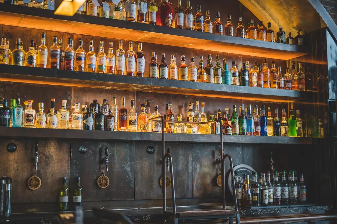 Shelves of bottles lit up behind a long bar