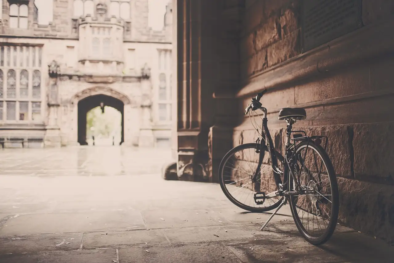 A bicycle leaning against an old stone wall near an arched gateway