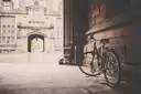A bicycle leaning against an old stone wall near an arched gateway