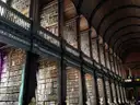 Tall shelves of old leather books and a carved gallery rail in the Long Room