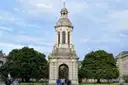 The stone bell tower in Trinity College's front square, on a green lawn under blue sky