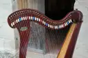 A wooden Celtic harp with coloured string pegs