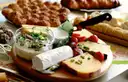 A wooden board with cheeses and a glass jar of dip