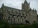Christ Church Cathedral in Dublin, a long grey stone church with a square tower, behind trees