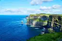 Green-topped cliffs and a sea stack on a sunny day at the Cliffs of Moher