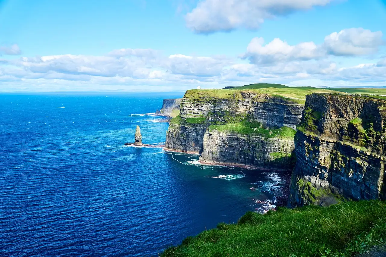 Green-topped cliffs and a sea stack on a sunny day at the Cliffs of Moher