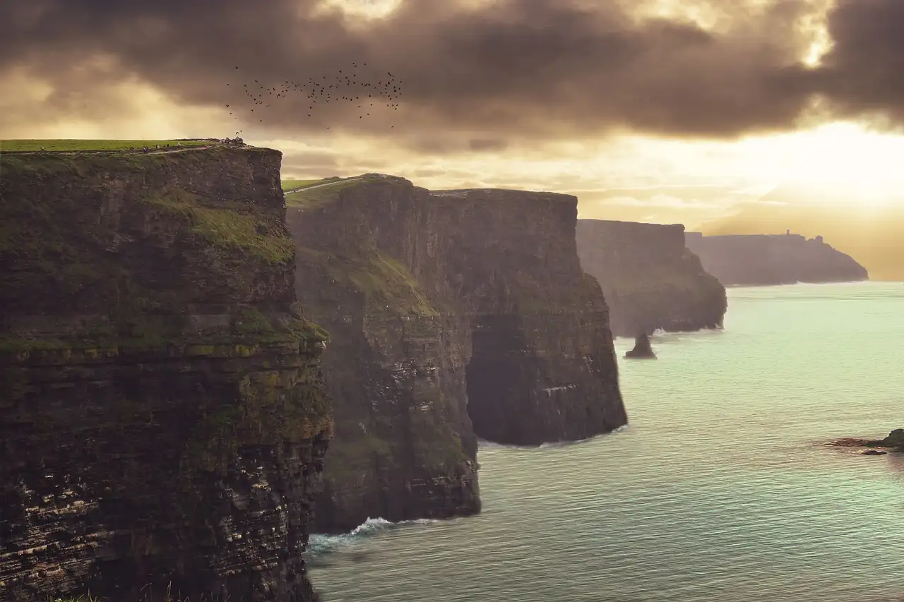 The Cliffs of Moher in warm evening light, with the sea calm below