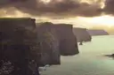 The Cliffs of Moher in warm evening light, with the sea calm below