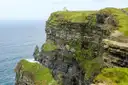 O'Brien's Tower on a green clifftop at the Cliffs of Moher, with the sea far below