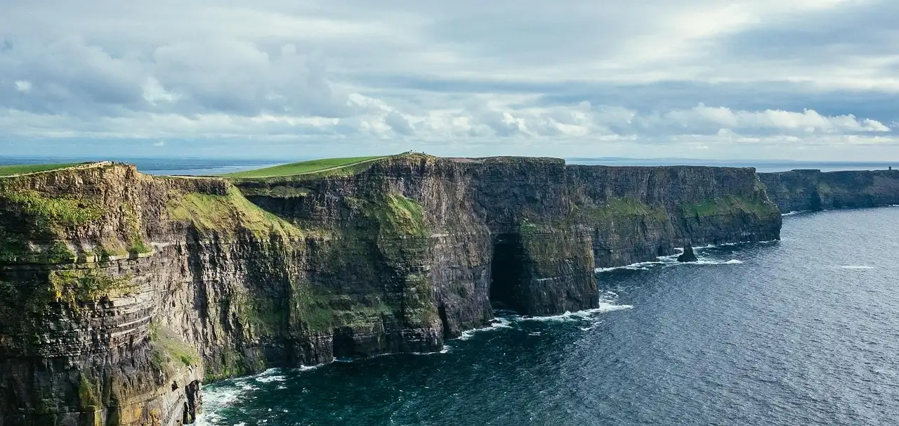 The Cliffs of Moher in a long line above the Atlantic under a cloudy sky