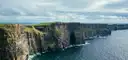 The Cliffs of Moher in a long line above the Atlantic under a cloudy sky