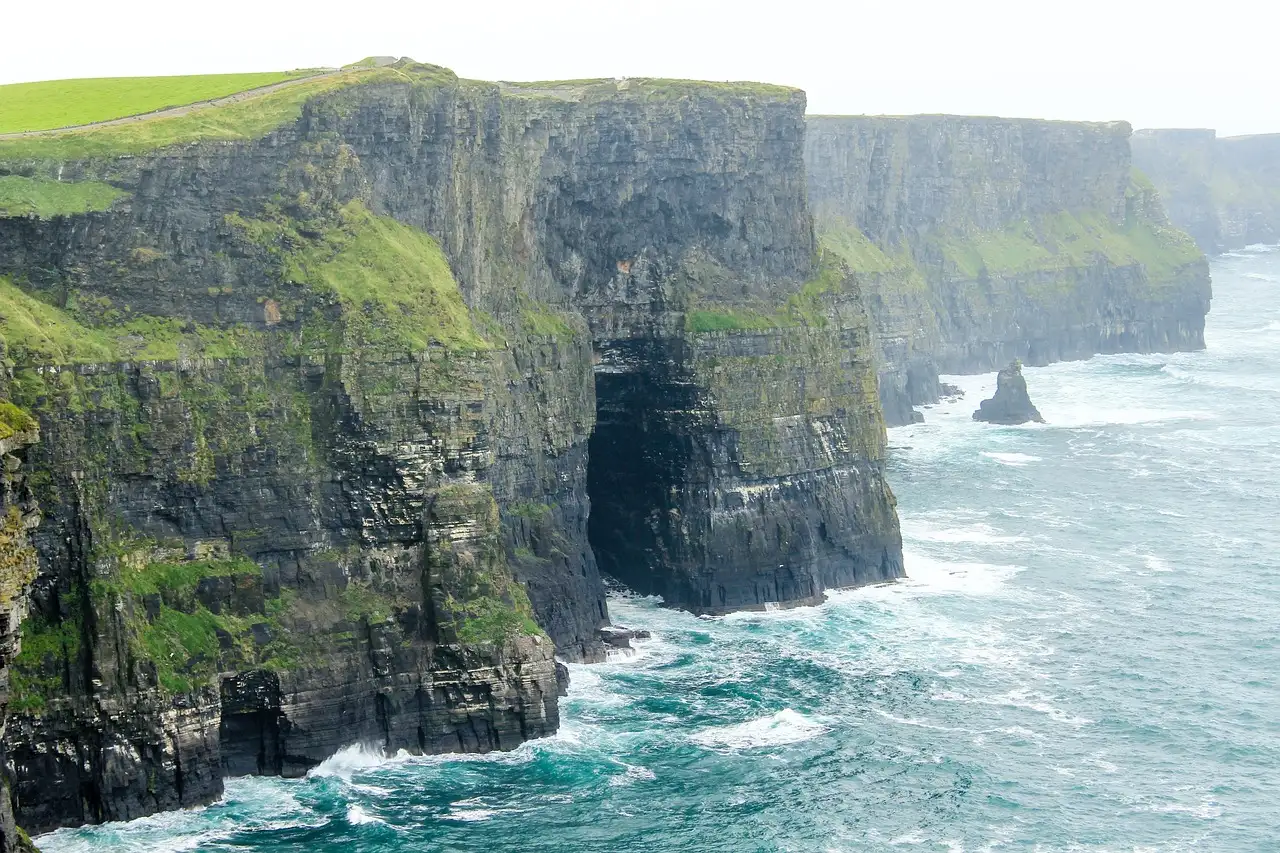 Dark cliff walls and sea caves at the Cliffs of Moher, with white surf below