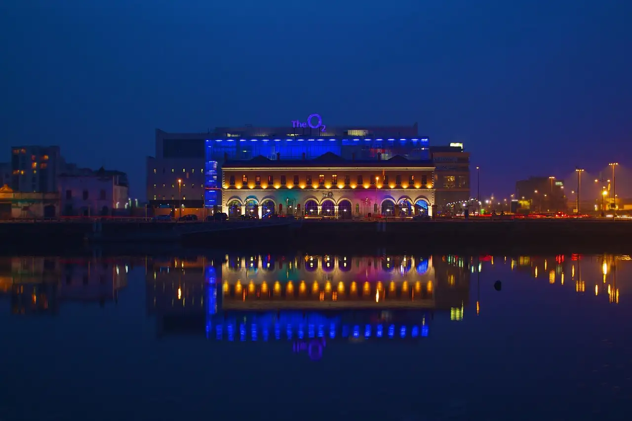 A Dublin riverside building lit blue at night and reflected in the water