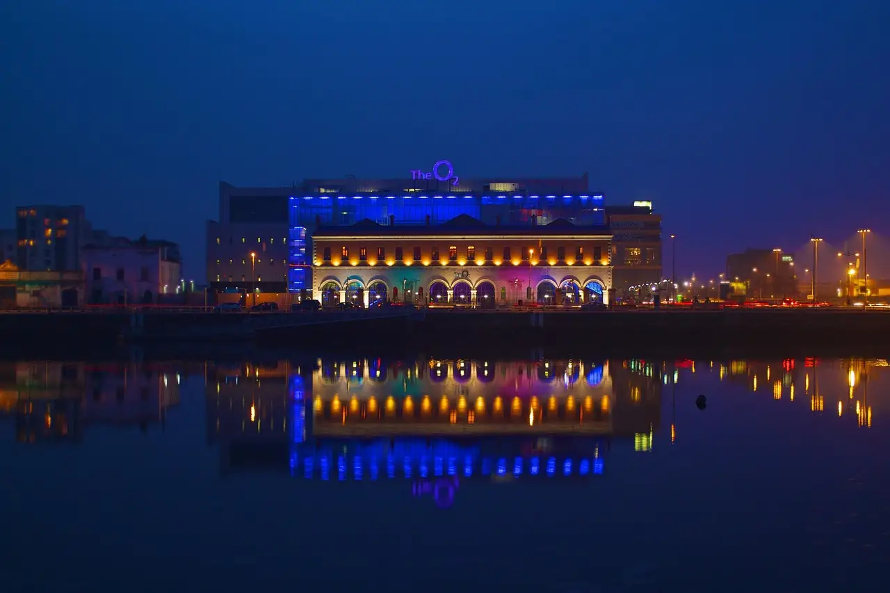 A Dublin riverside building lit blue at night and reflected in the water
