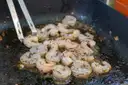 Prawns frying in a pan with herbs