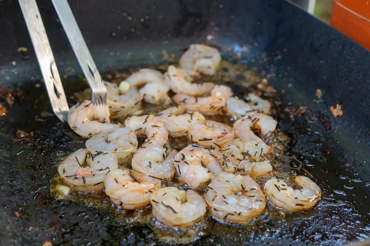 Prawns frying in a pan with herbs