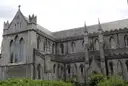 The long grey stone side of Christ Church Cathedral in Dublin, behind a green lawn