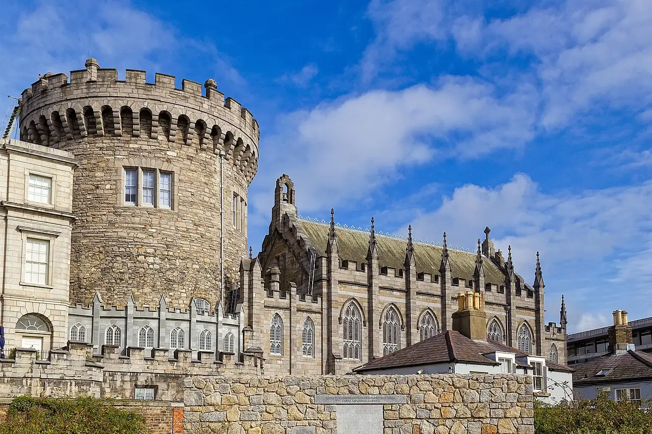 The round stone Record Tower of Dublin Castle beside the grey Gothic Chapel Royal, under a blue sky