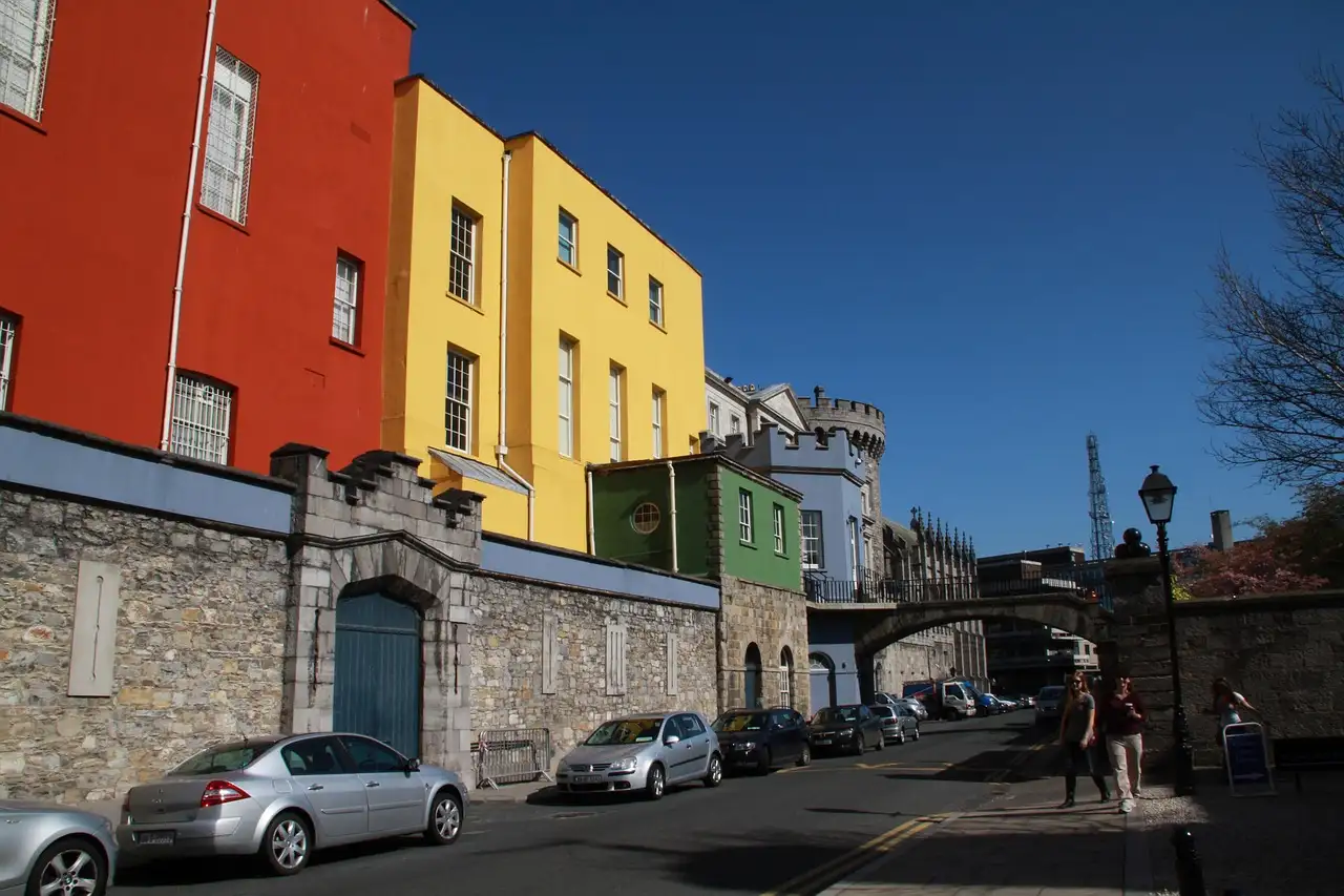 Old stone walls and painted houses of Dublin Castle seen from the street outside