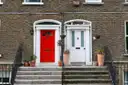 A red and a white Georgian front door side by side on a brick house in Dublin