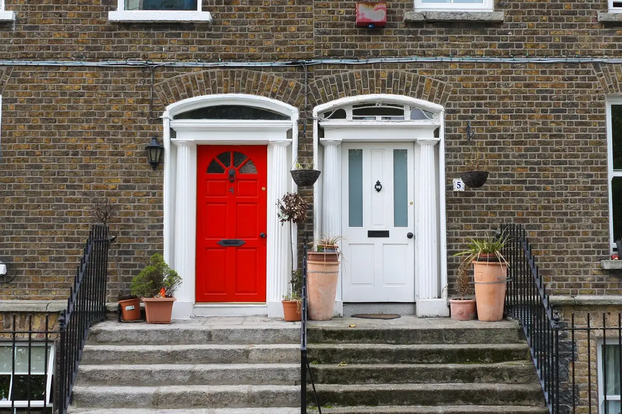 A red and a white Georgian front door side by side on a brick house in Dublin