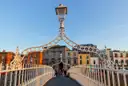 The Ha'penny Bridge in Dublin in evening sun, looking along the deck under one of its iron lamp arches