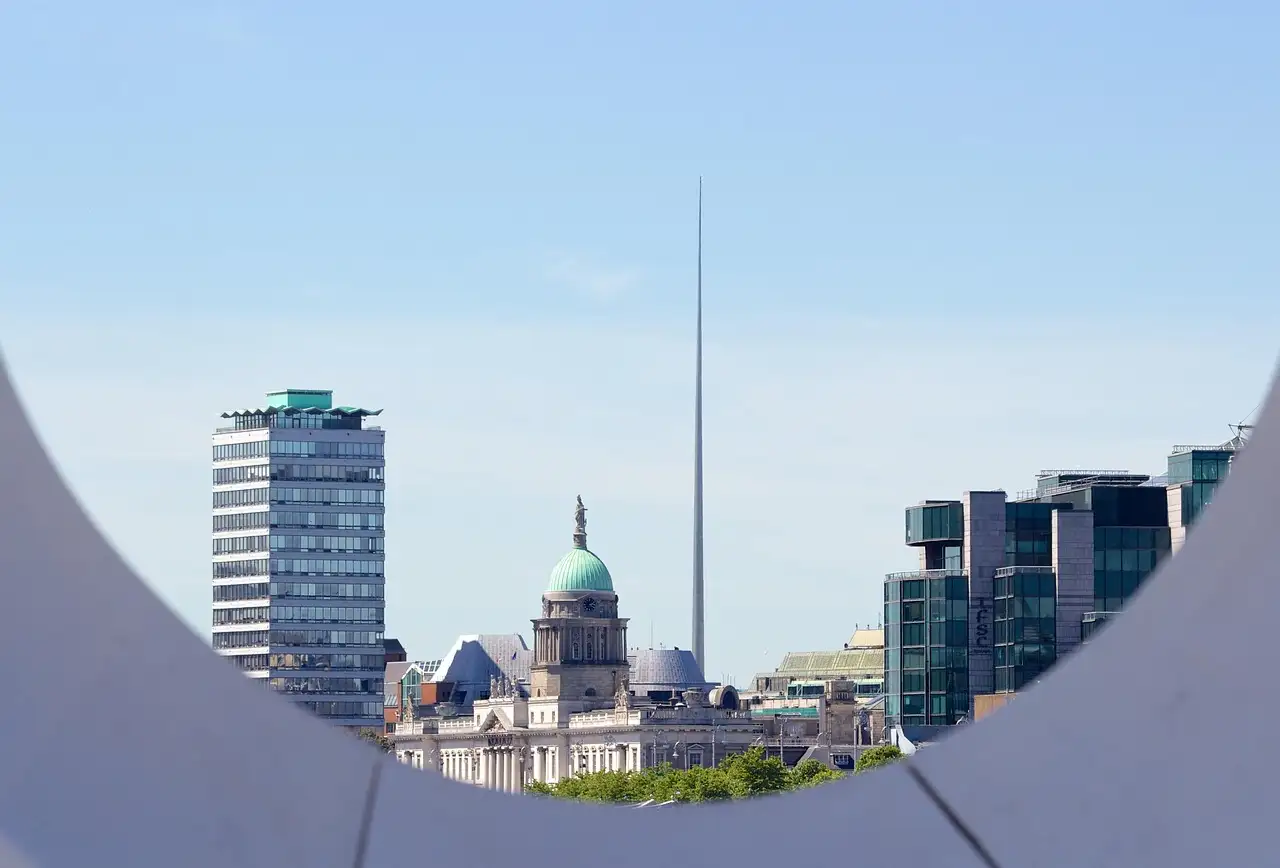 Dublin's skyline seen through the curve of a bridge, with the Spire and the Custom House dome