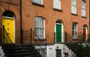 A terrace of red-brick houses with differently coloured front doors