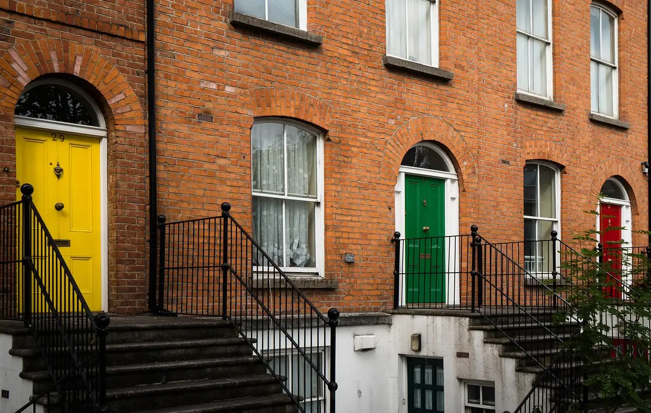 A terrace of red-brick houses with differently coloured front doors