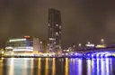 Belfast's River Lagan waterfront at night with lit buildings reflected in the water (the line's destination; no photo of the train itself)