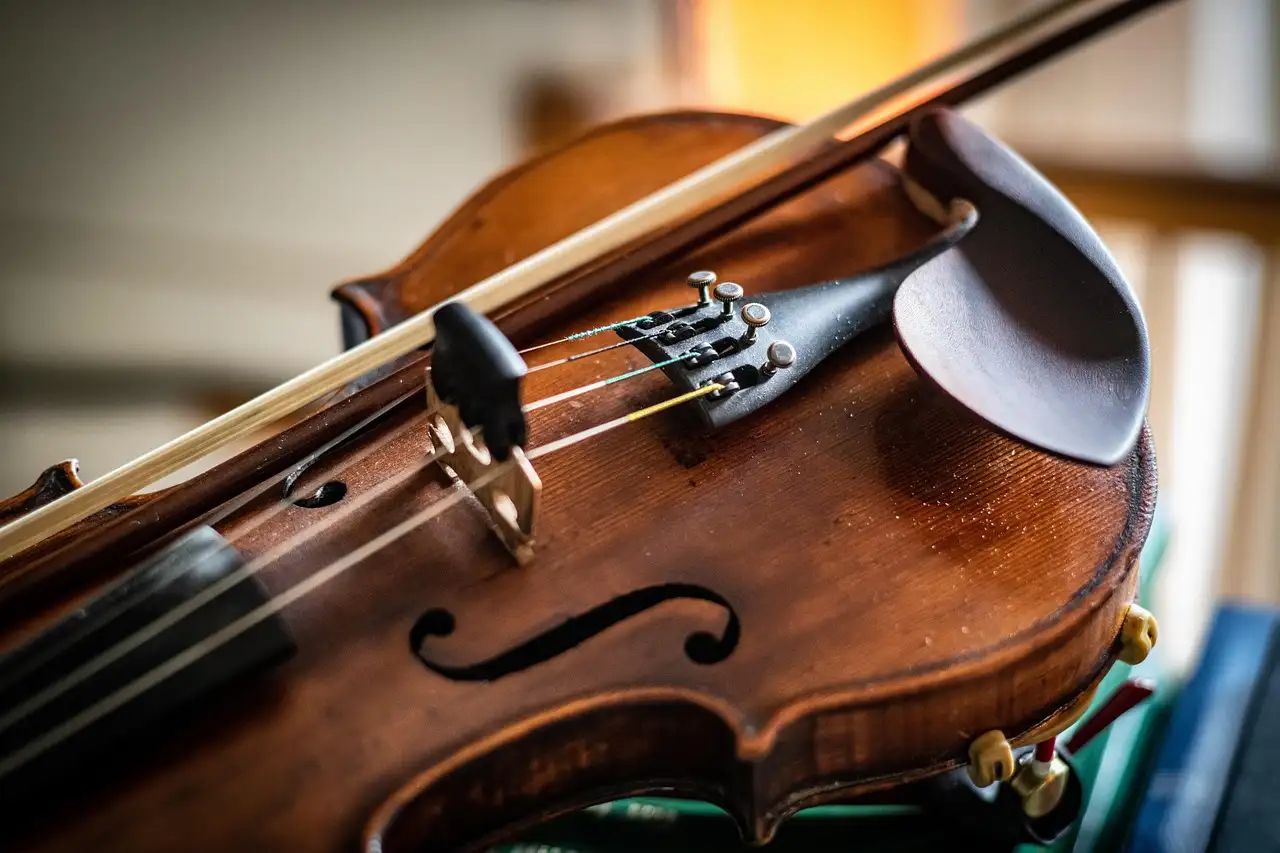 A fiddle and its bow resting on a table in warm light