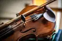 A fiddle and its bow resting on a table in warm light