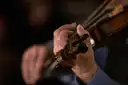 Close-up of hands playing a fiddle in a dark room