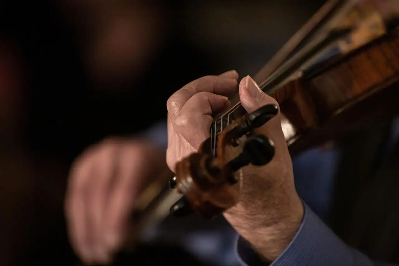 Close-up of hands playing a fiddle in a dark room