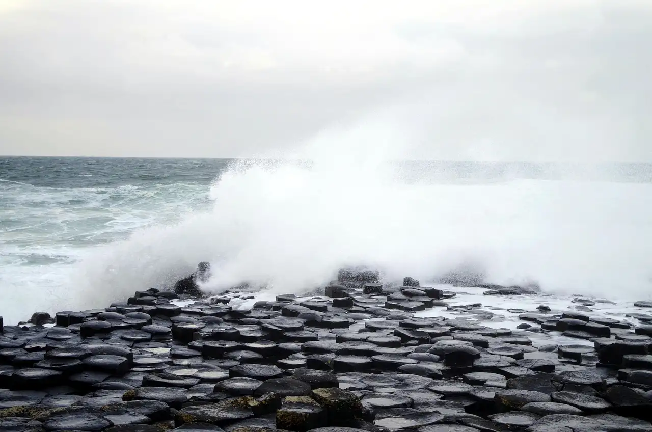 A wave breaking over the dark basalt stones of the Giant's Causeway