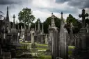 Rows of tall stone crosses and grave monuments at Glasnevin Cemetery under a cloudy sky