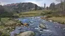 The round tower of Glendalough above a rocky river in the valley