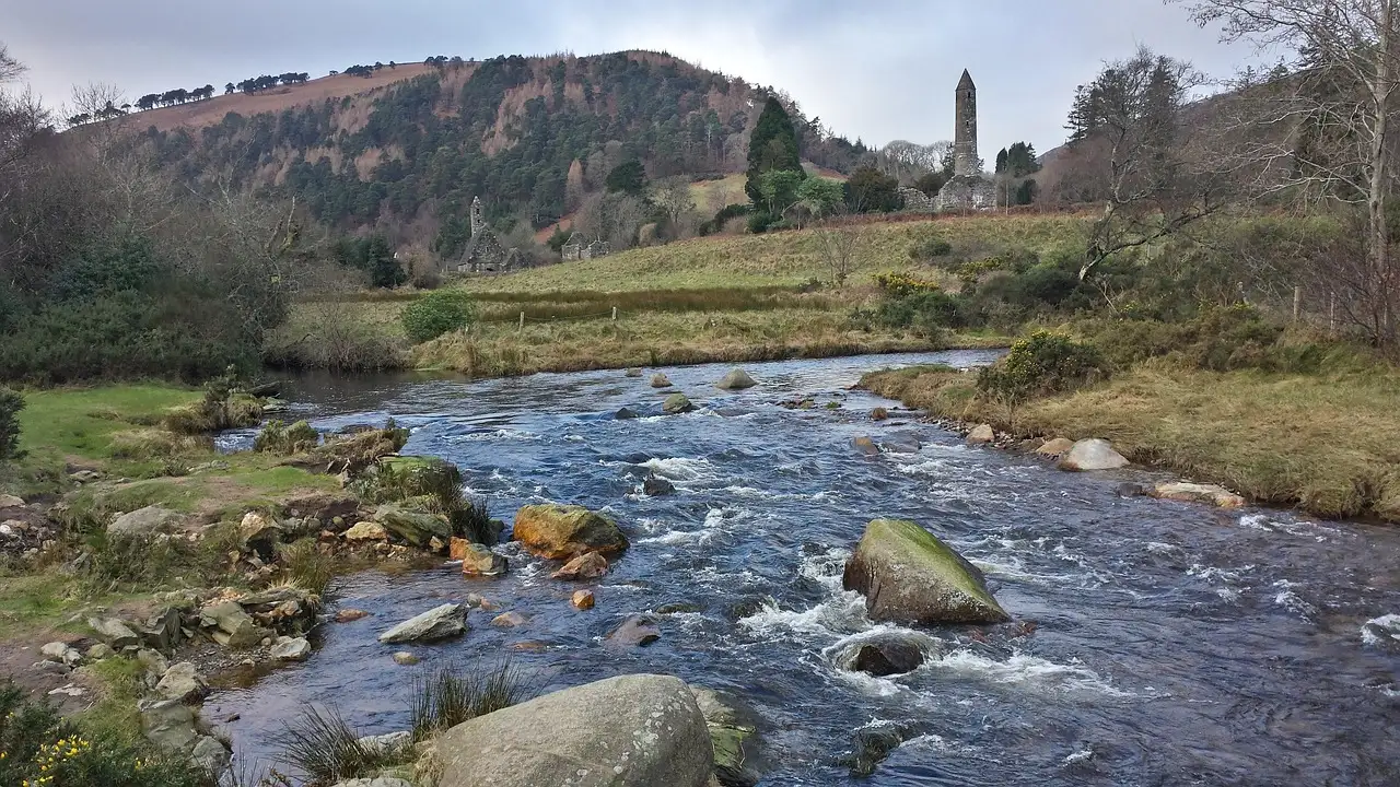 The round tower of Glendalough above a rocky river in the valley