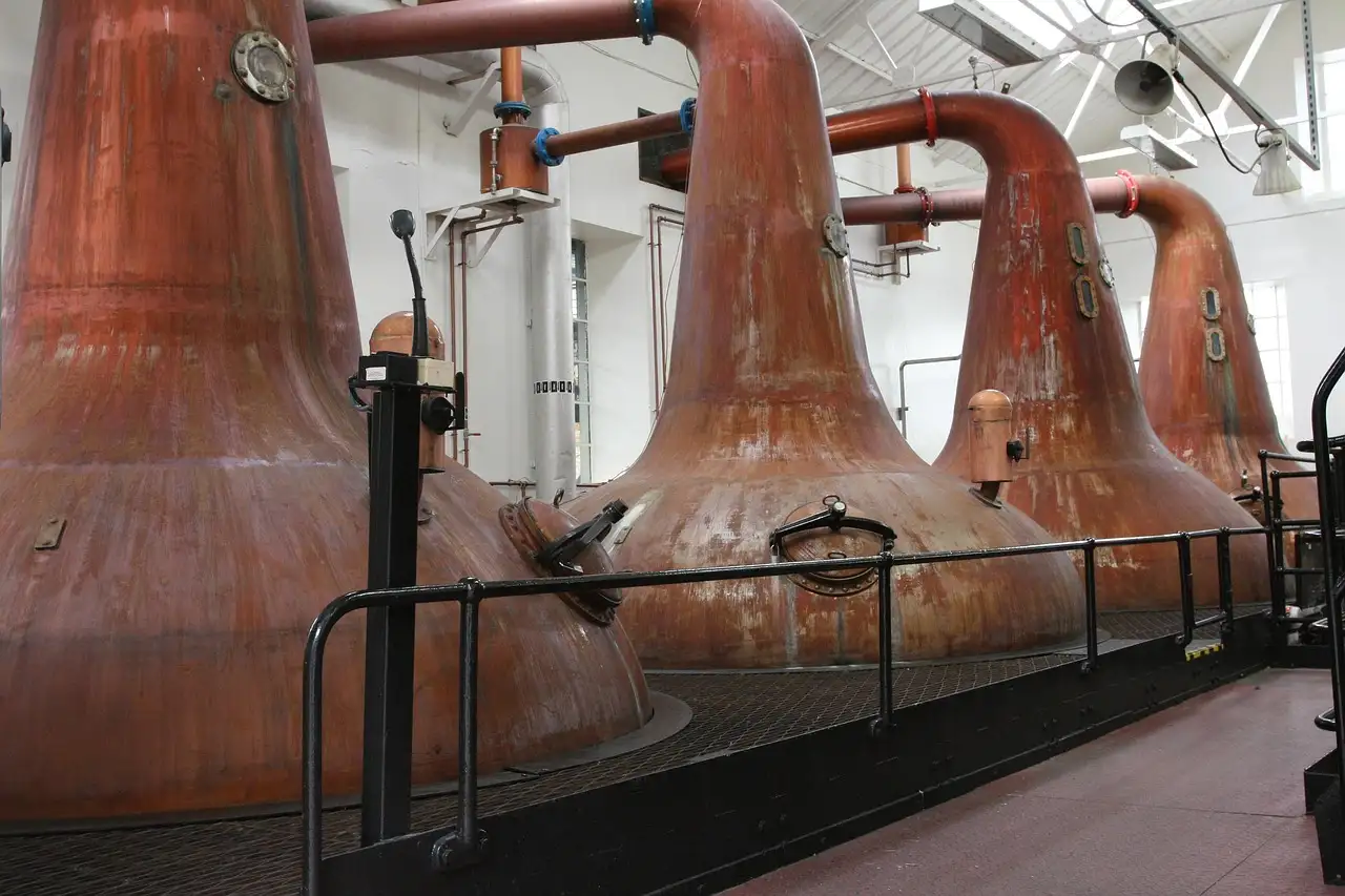 A row of large copper pot stills in a distillery hall