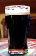 A pint of stout on a wooden pub table