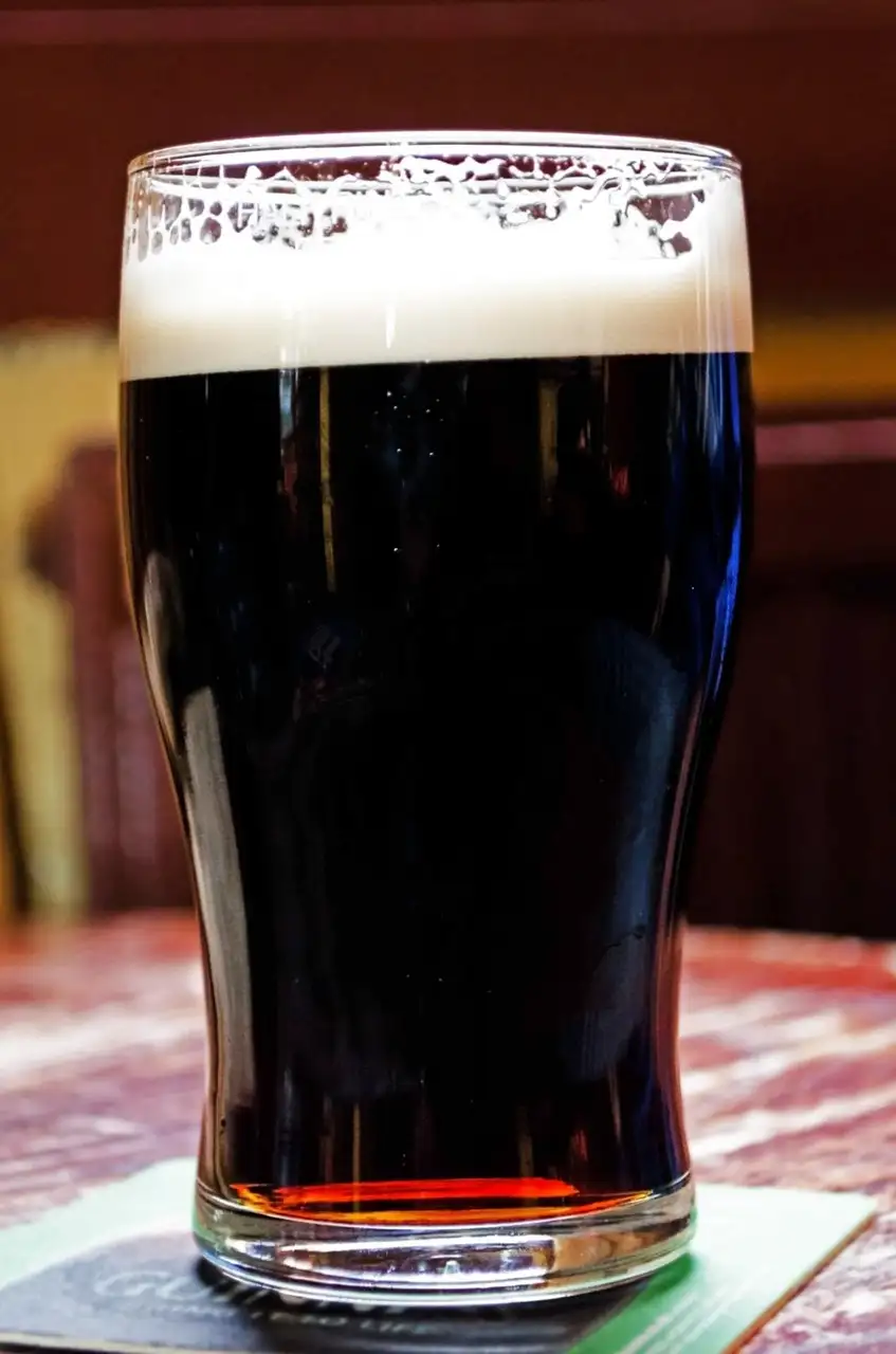 A pint of stout on a wooden pub table