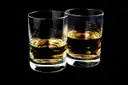 Two tumblers of whiskey on a black background