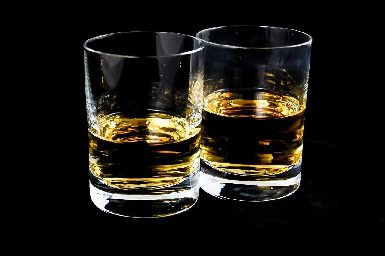 Two tumblers of whiskey on a black background