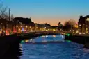 The Ha'penny Bridge lit up over the River Liffey at dusk, with the quays glowing behind