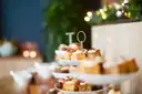Cakes on a tiered stand with fairy lights blurred behind