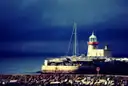 The white harbour lighthouse at Howth, with boats beside the pier