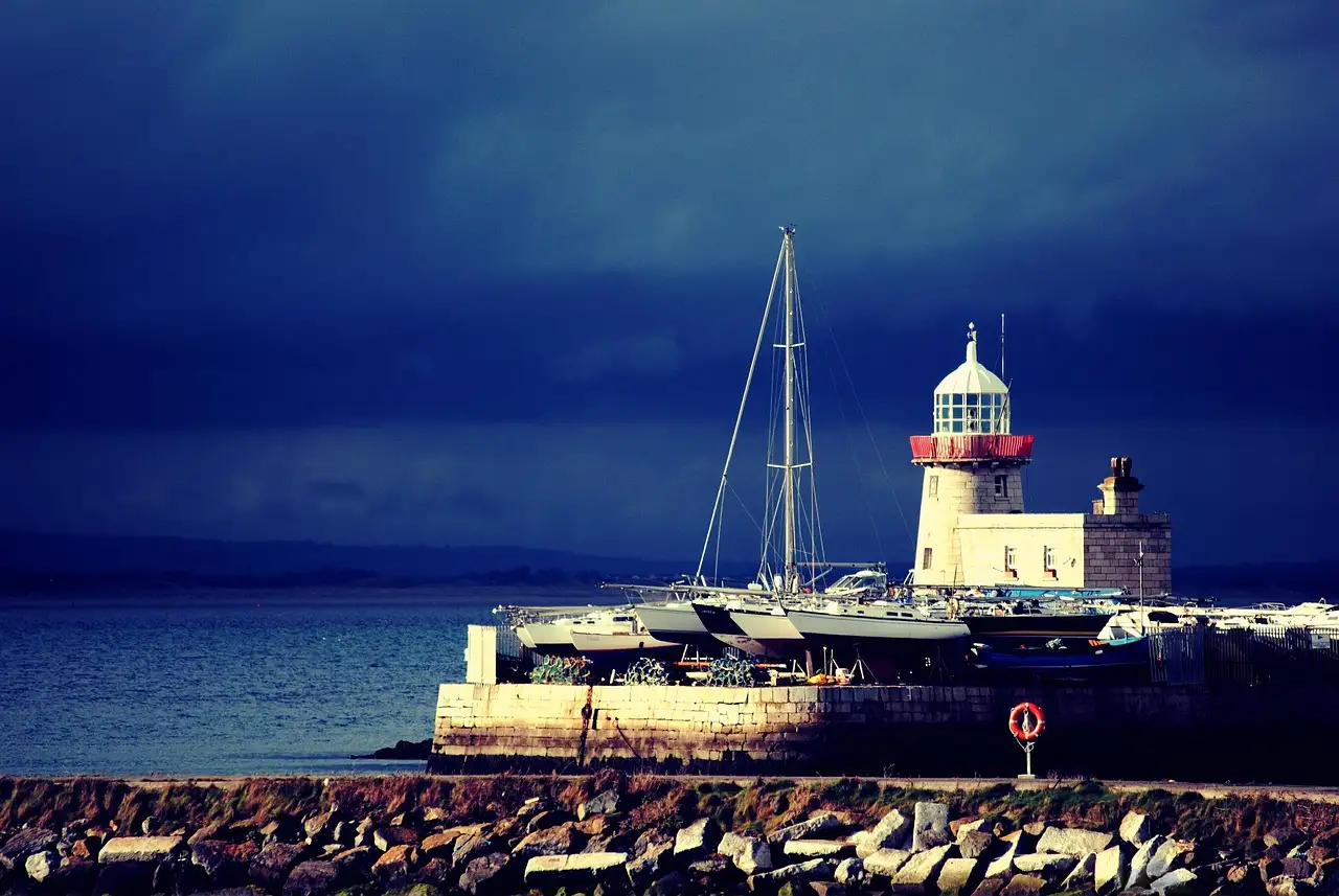 The white harbour lighthouse at Howth, with boats beside the pier