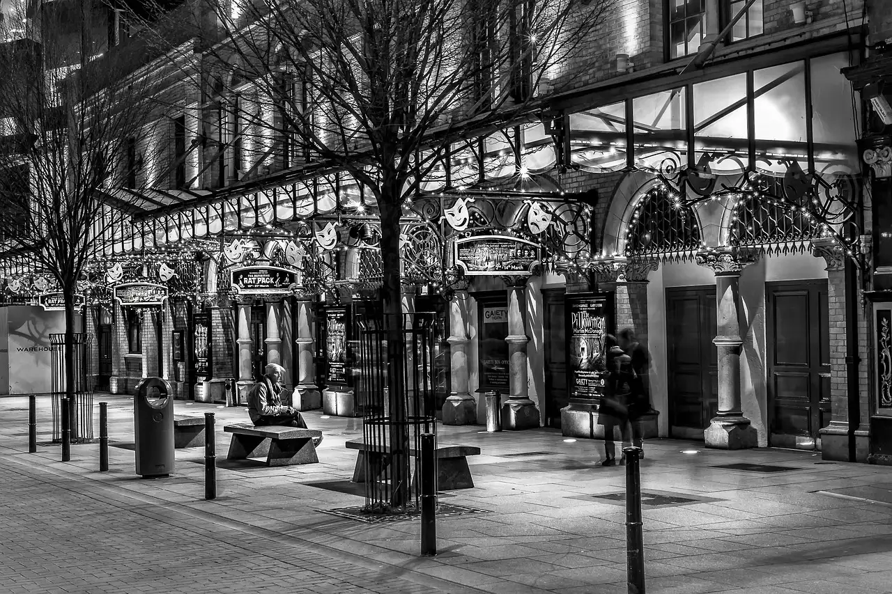 A lamp-lit Dublin street at night in black and white, with a theatre front