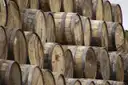 Rows of oak whiskey casks stacked on their sides in a warehouse