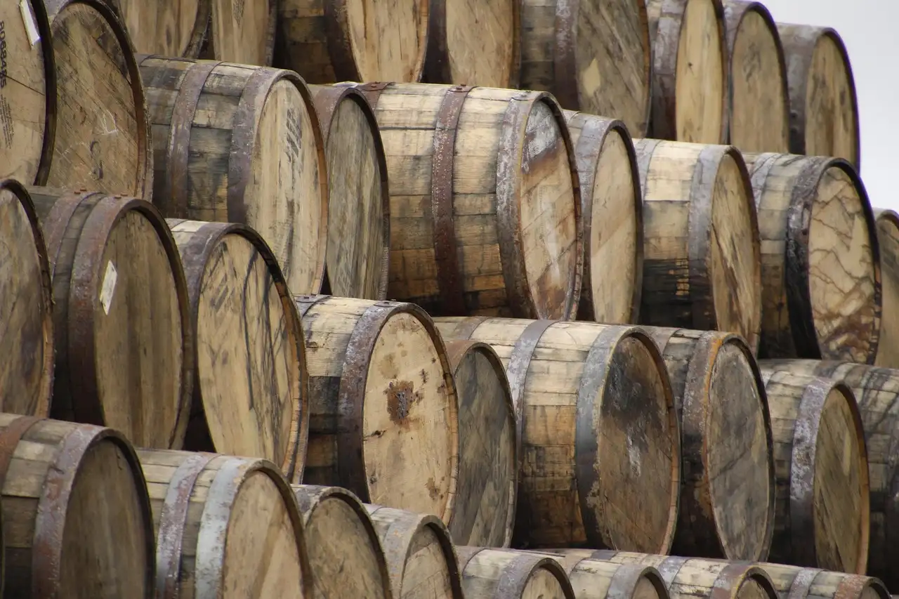 Rows of oak whiskey casks stacked on their sides in a warehouse